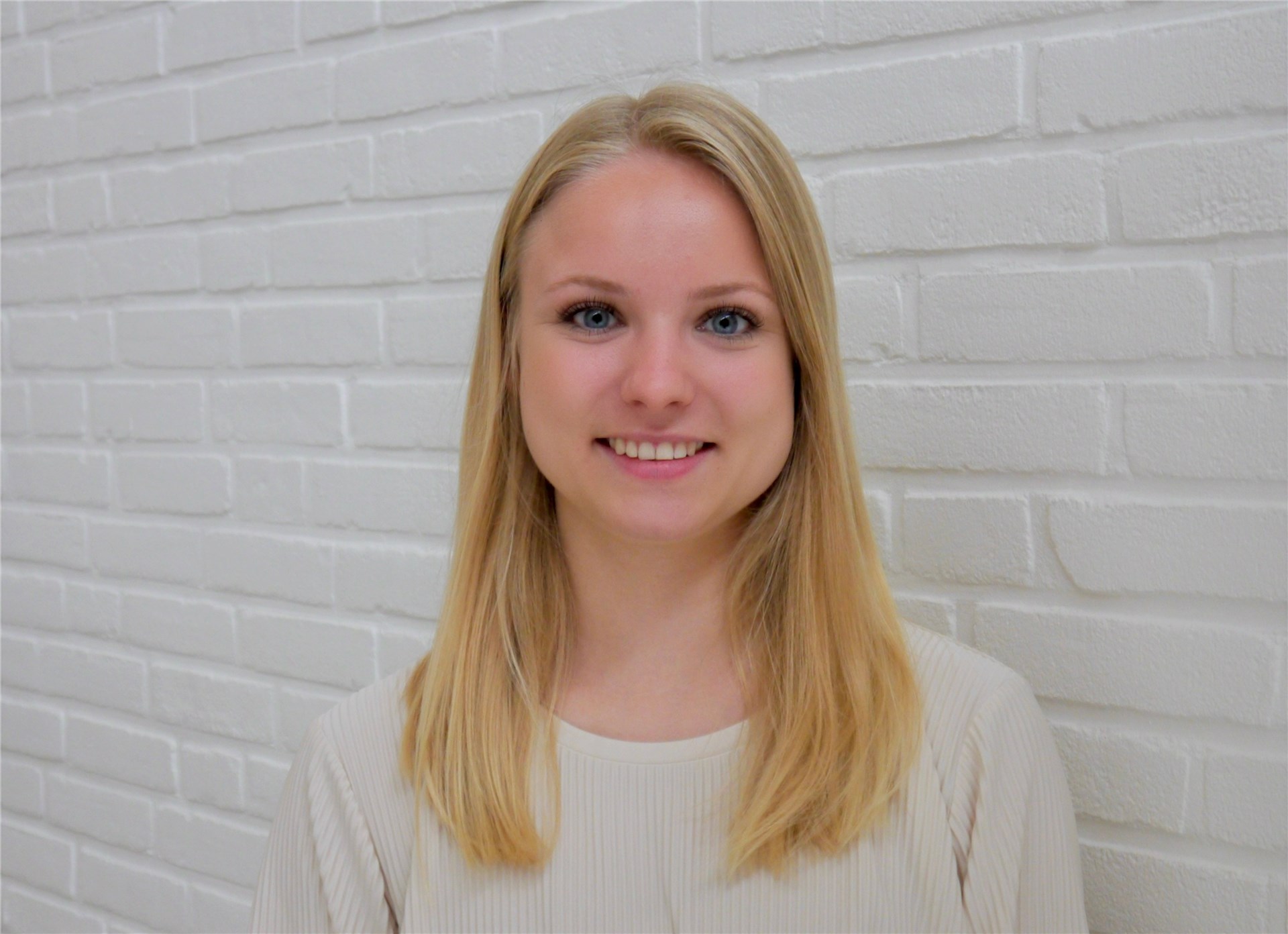 Eine junge blonde Frau lächelt in die Kamera