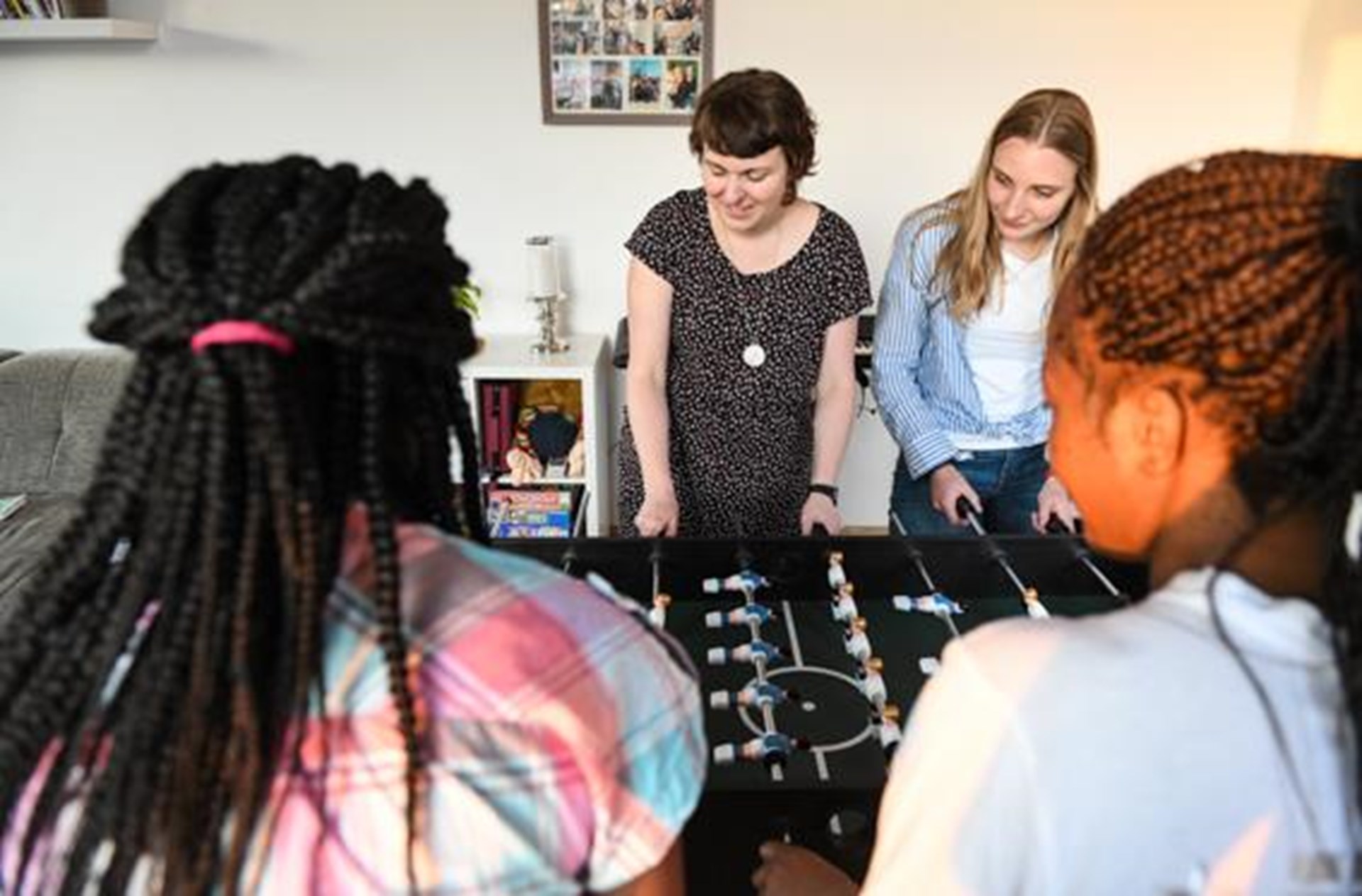 junge engagierte Frauen beim Tischkicker spielen mit geflüchteten Mädchen